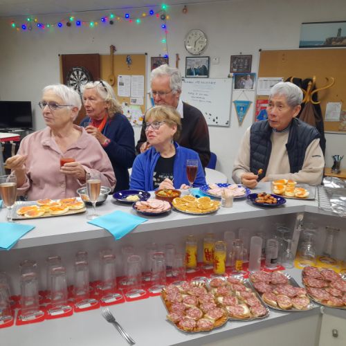 Au 1er plan, las canapés au saucisson attendent patiemment. Au 2ème plan, des convives attentifs.